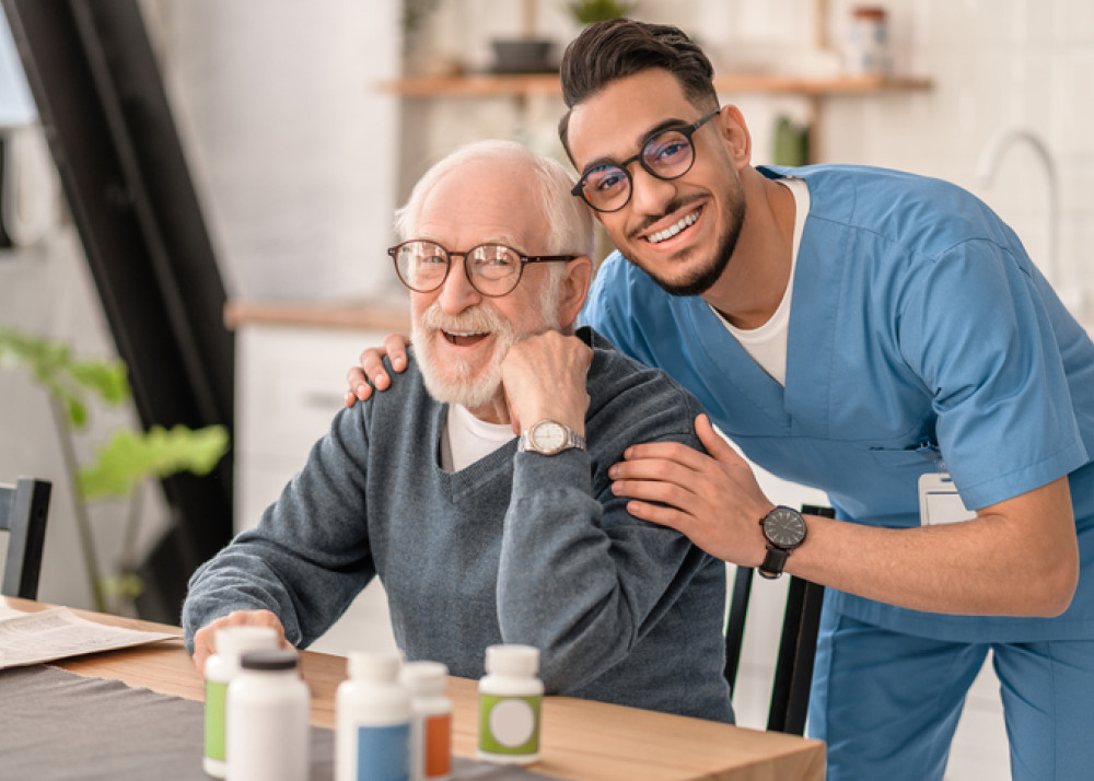 Friendly male caregiver offering social support to a senior man, showcasing the engaging and supportive interaction available with a Level 1 home care package.