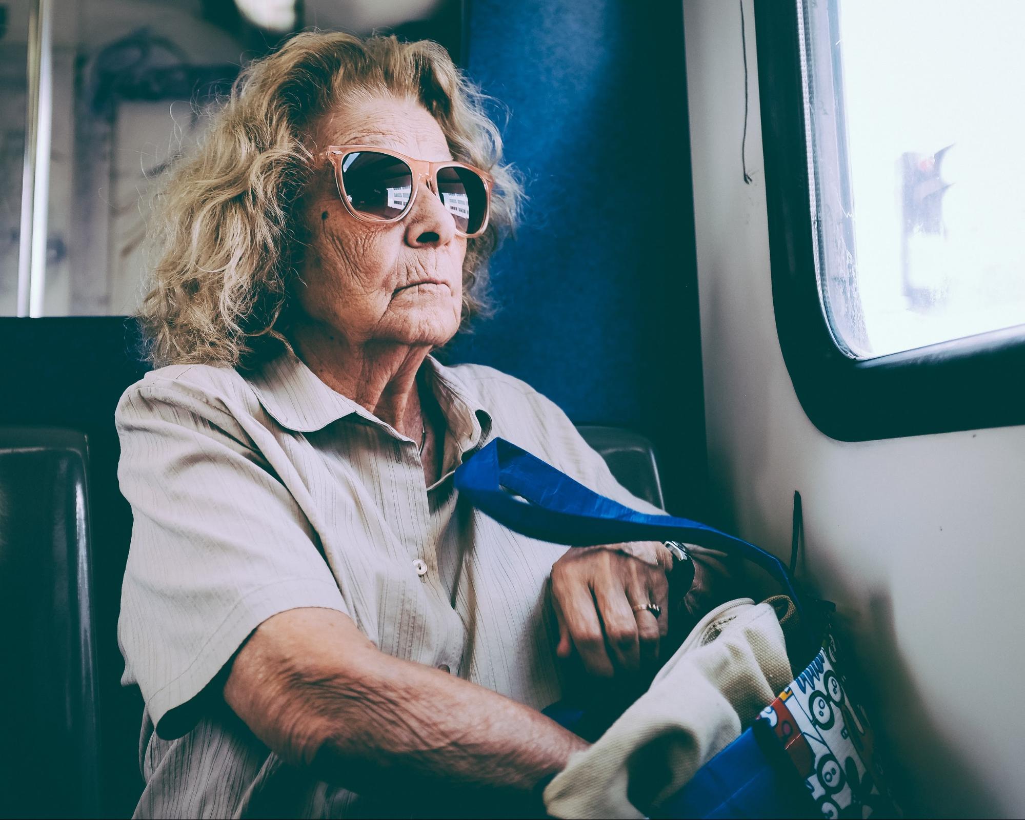 Older woman in sunglasses on public transport - Early Signs of Dementia - Focus Care