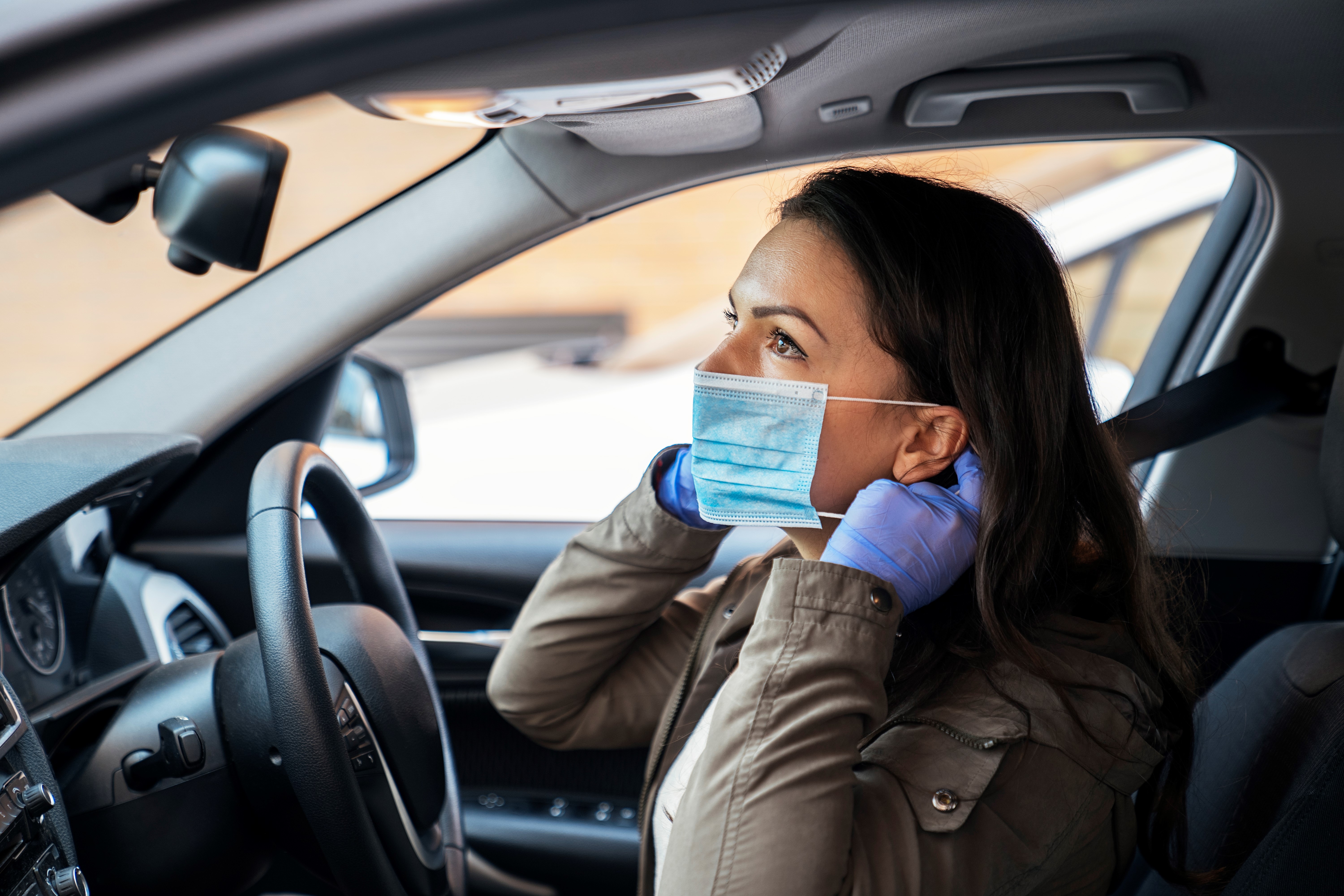 Woman puts on a mask whilst wearing disposable gloves in her car - The Benefits of In-Home Nursing - Focus Care