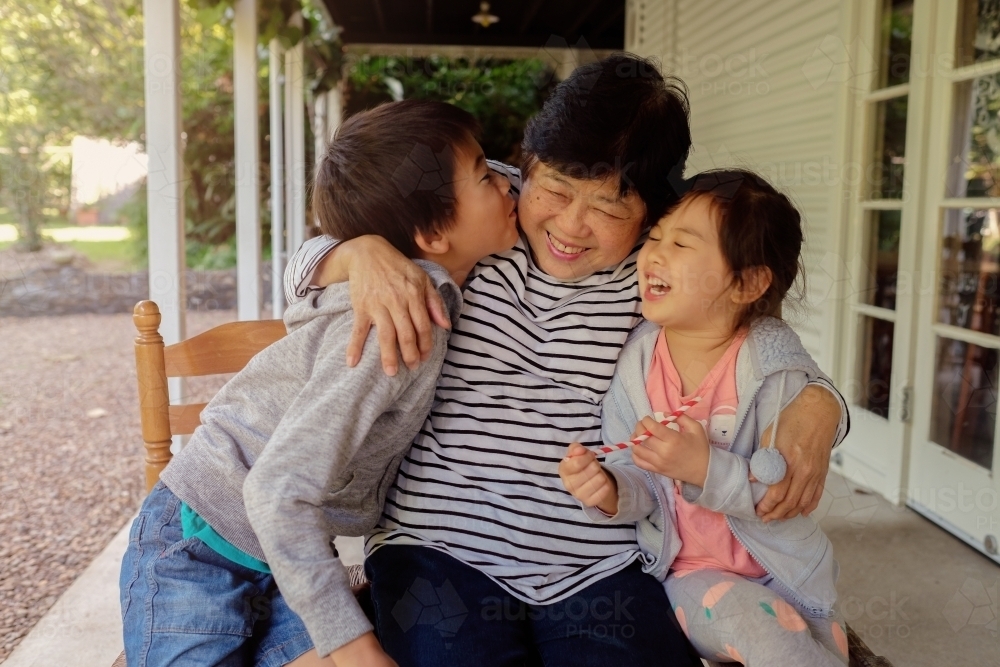 A grandmother and her two grandchildren, embracing and laughing - Home Care Packages - Focus Care