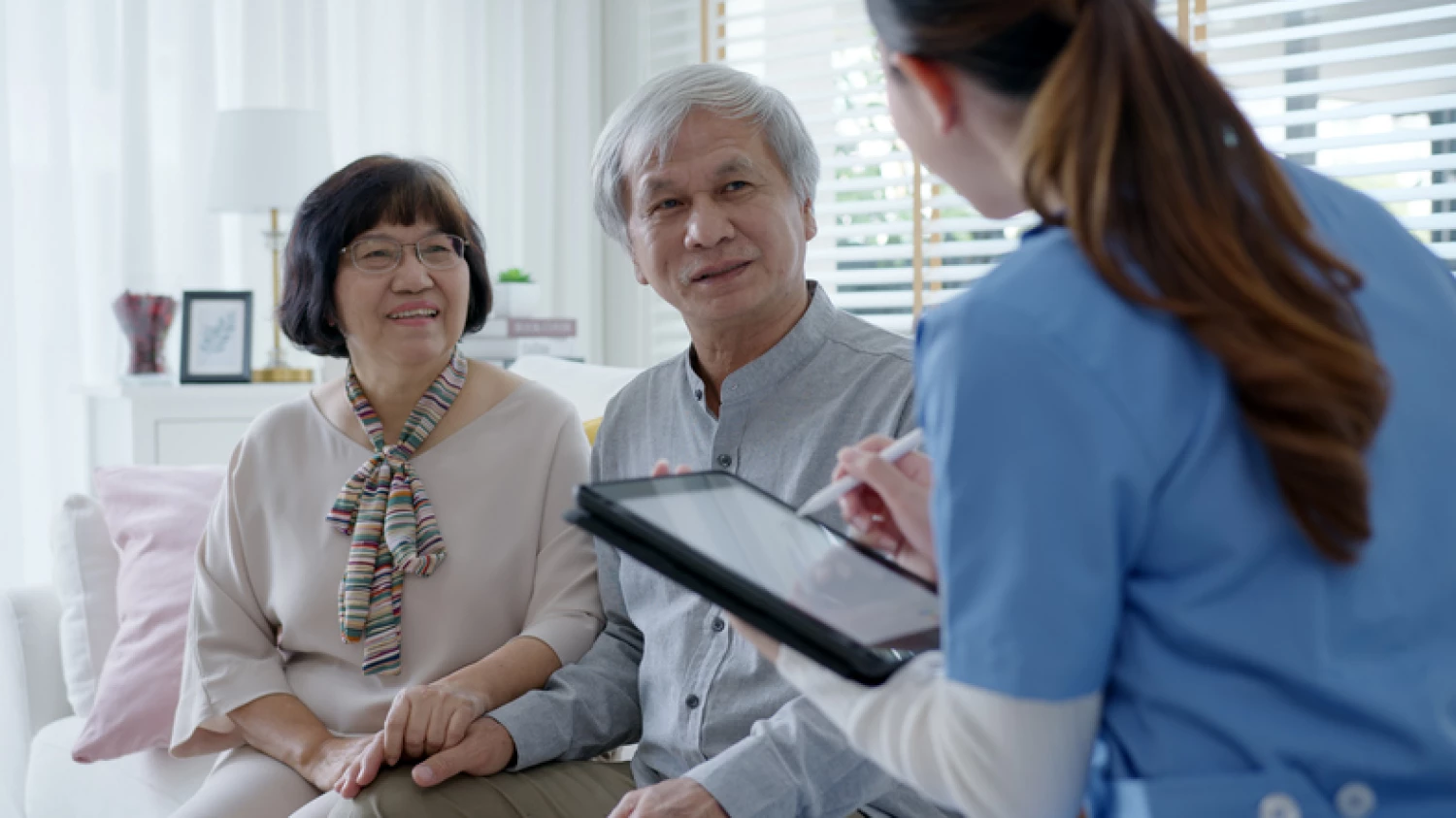 Elderly couple sitting together and speaking with a healthcare professional, highlighting the role of medical assessments in diagnosing dementia.