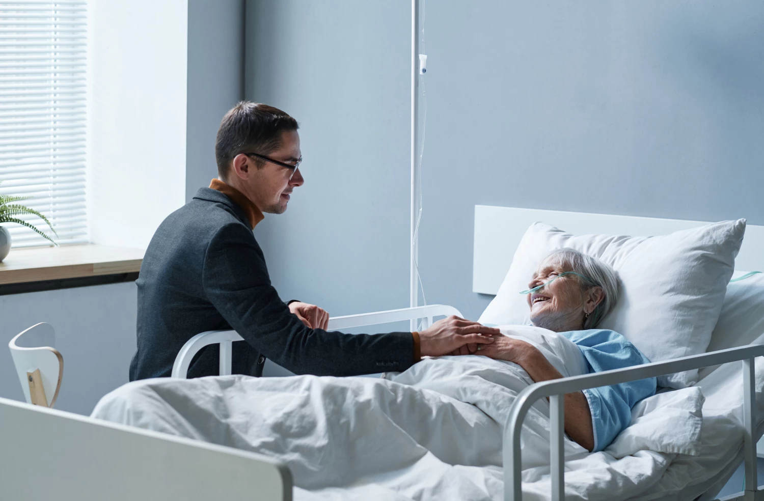 son visiting mother at palliative care, they are talking as she lays in bed