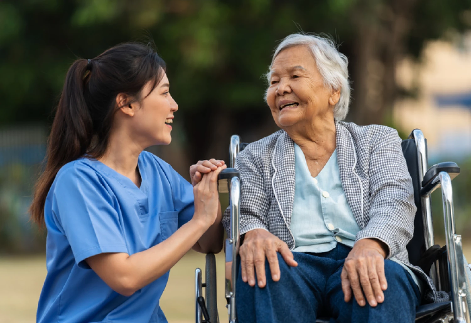 Nurse providing private in-home care to an elderly woman in a wheelchair.