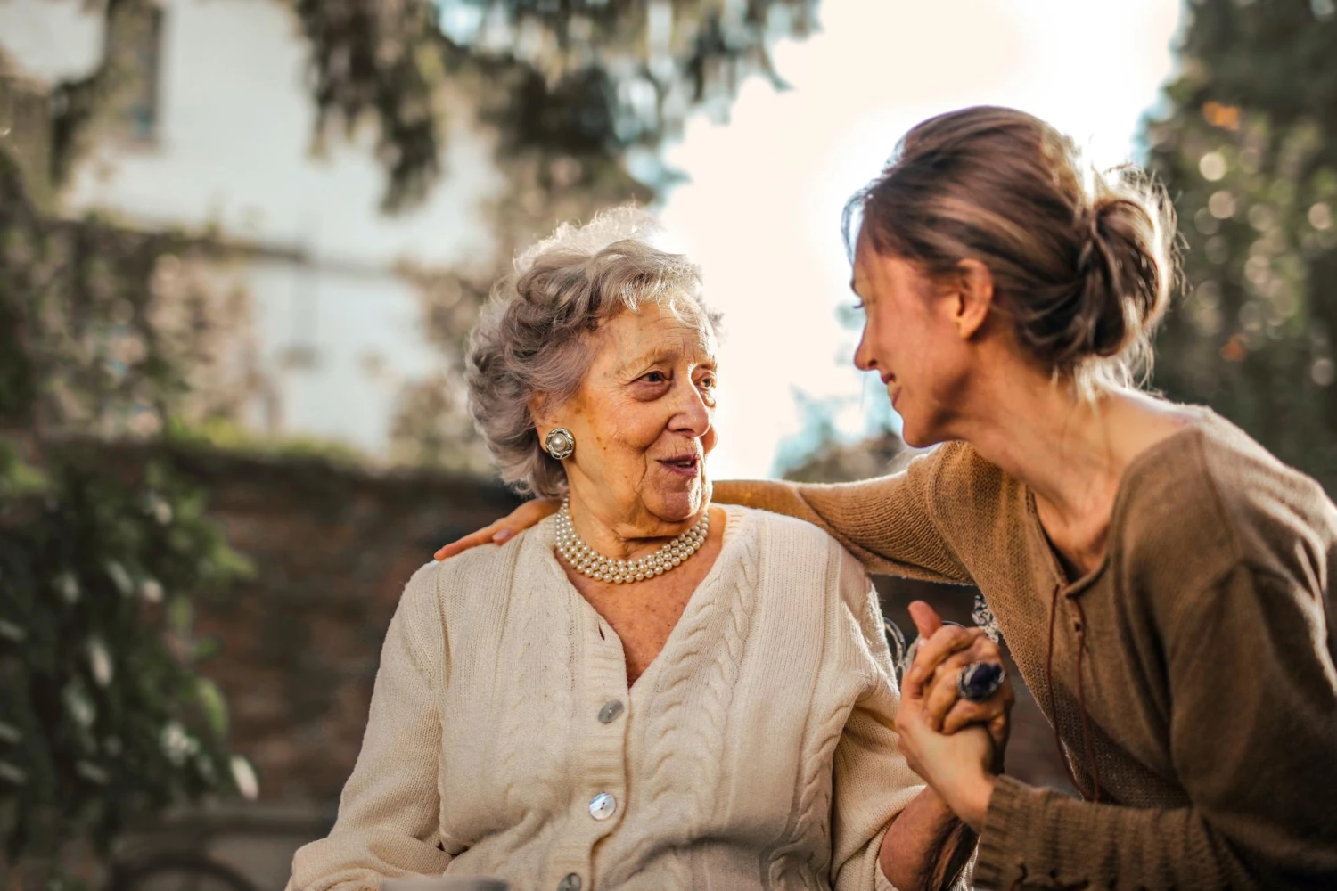 Two woman of different generations smiling together holding hands - Focus Care
