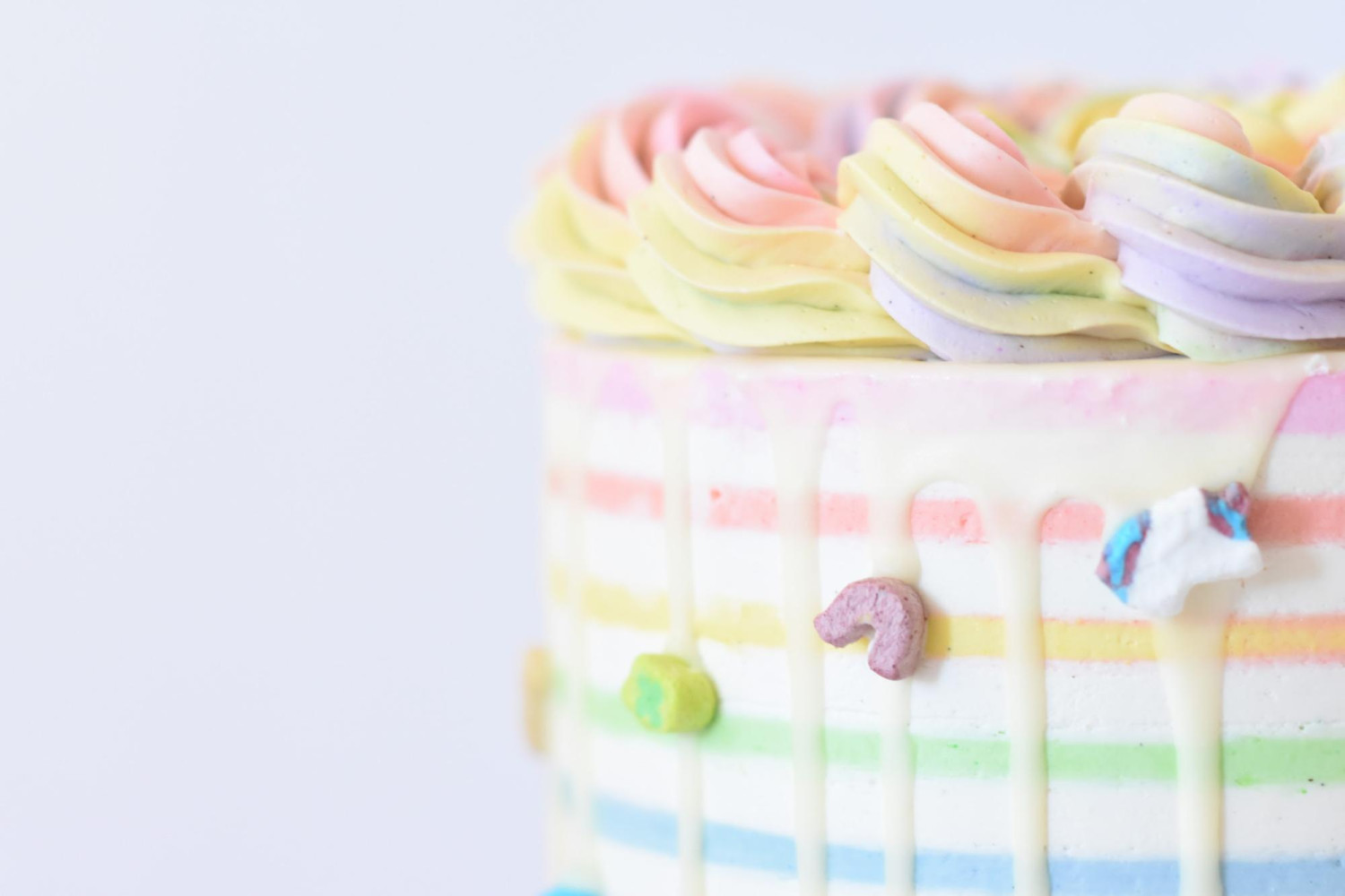 Birthday cake with colourful icing, charms and stripes.