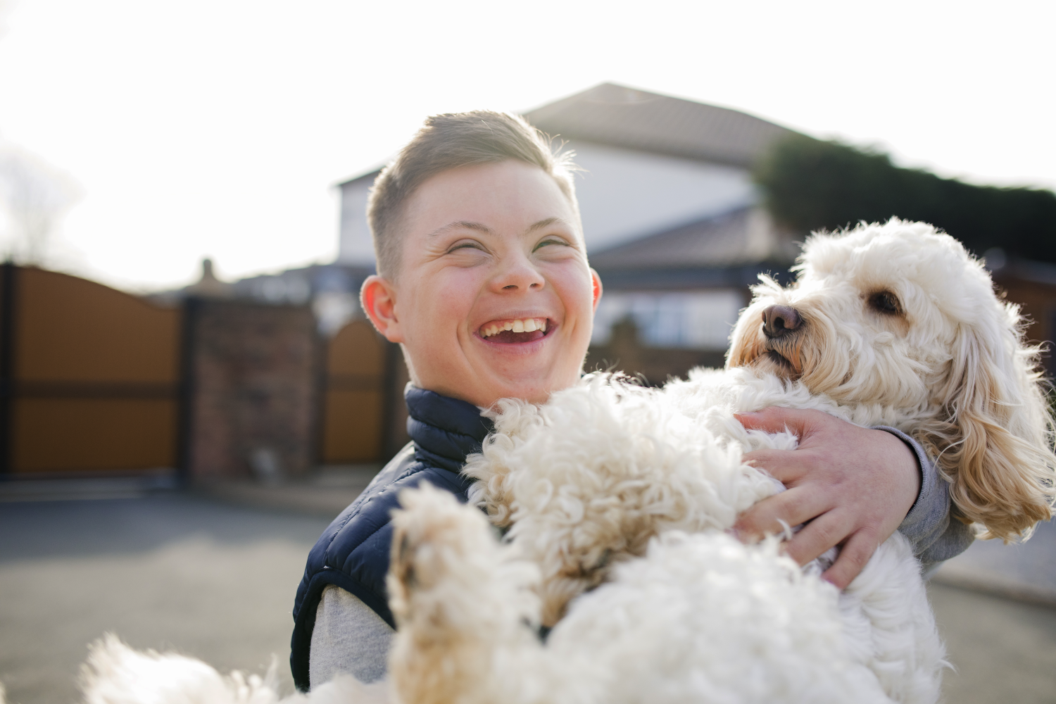 A boy with Down Syndrome holding a dog and smiling - 5 Tips to Know Before Your NDIS Plan Review - Focus Care