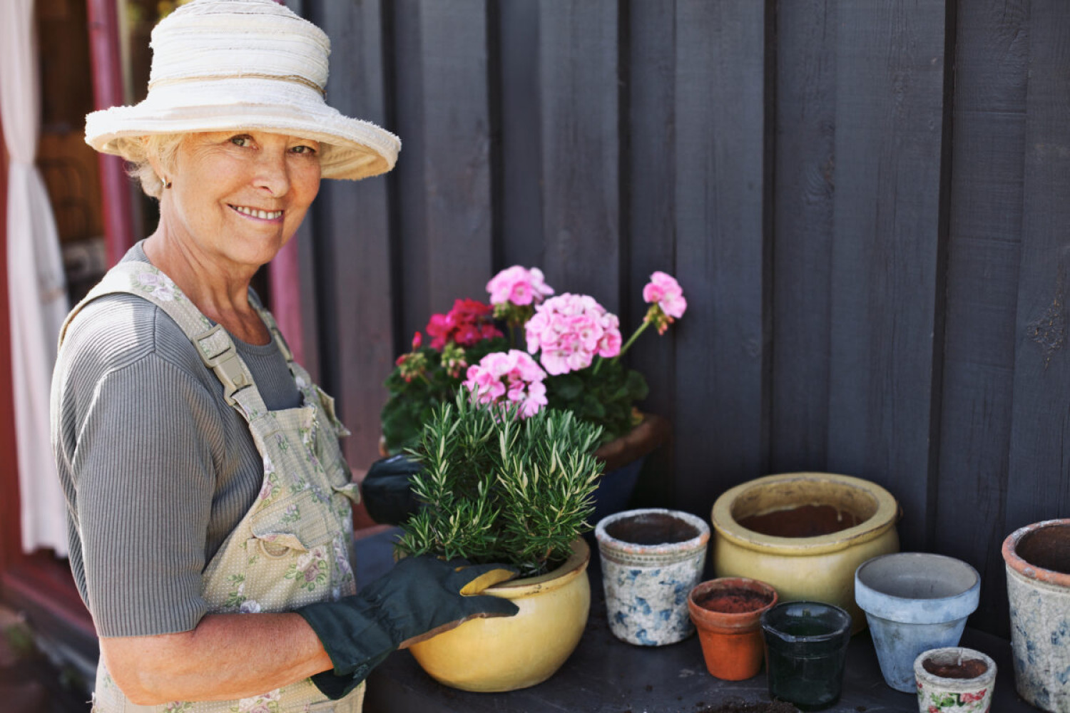 Elderly woman holding a bunch of light and dark pink flowers.