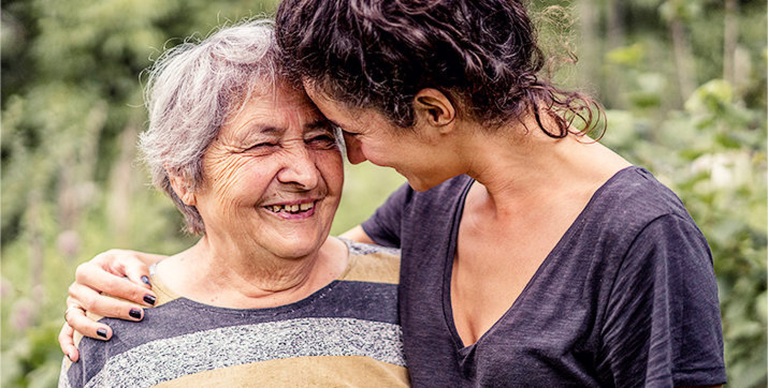An elderly woman in a loving embrace with a younger woman.