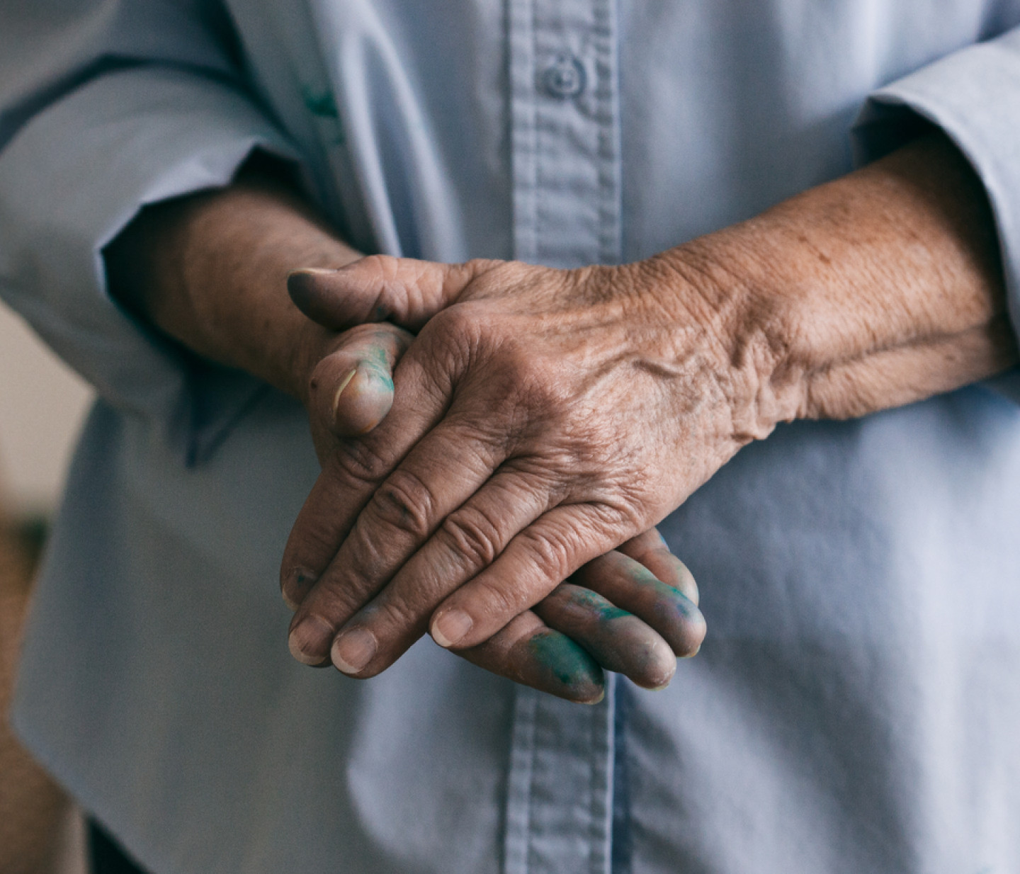 Older woman's hands with blue pain on them.
