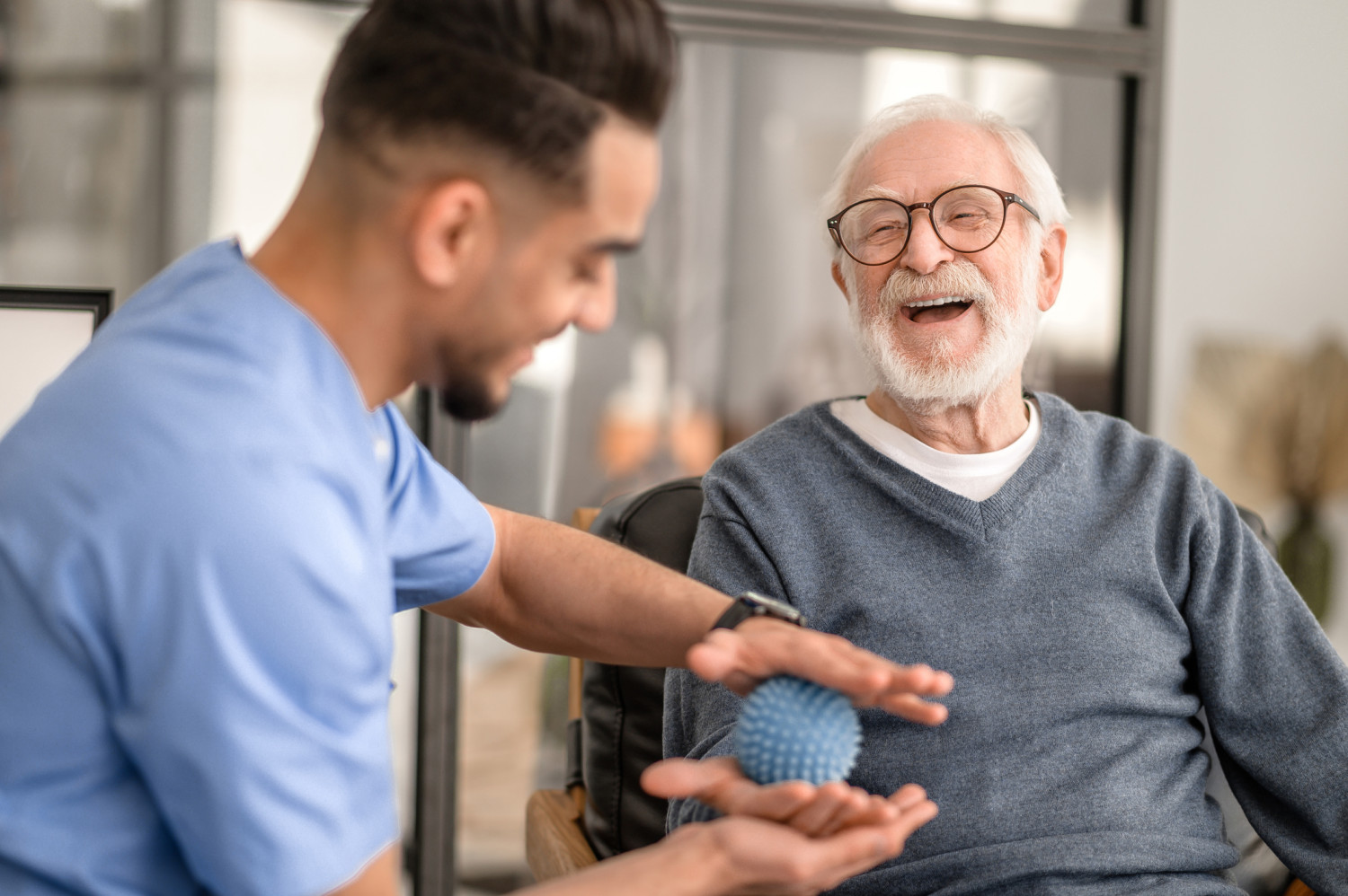 A senior gentleman shares a joyful moment with an allied health physiotherapist during a rehabilitation session, highlighting the therapeutic relationship and the commitment to enhancing mobility and independence in the elderly.