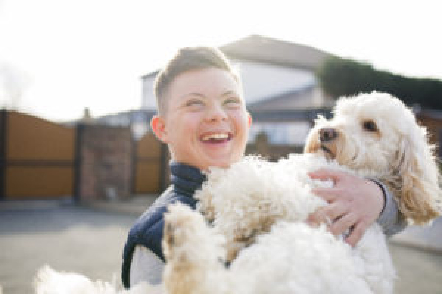 A boy with Down Syndrome happily holding a dog.