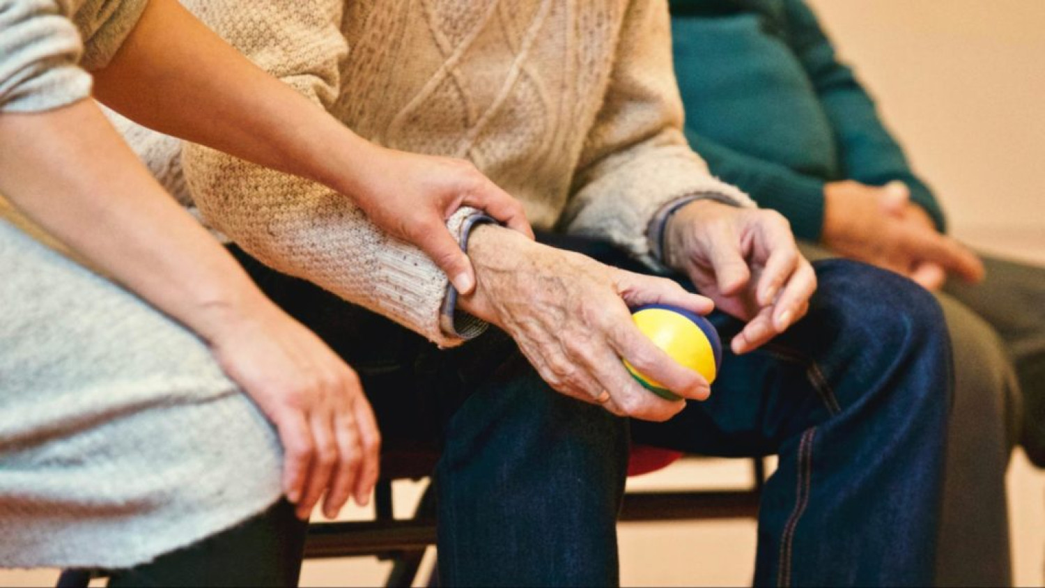 Elderly man supported by care worker holding a ball. Exercise for arthritis, Focus Care