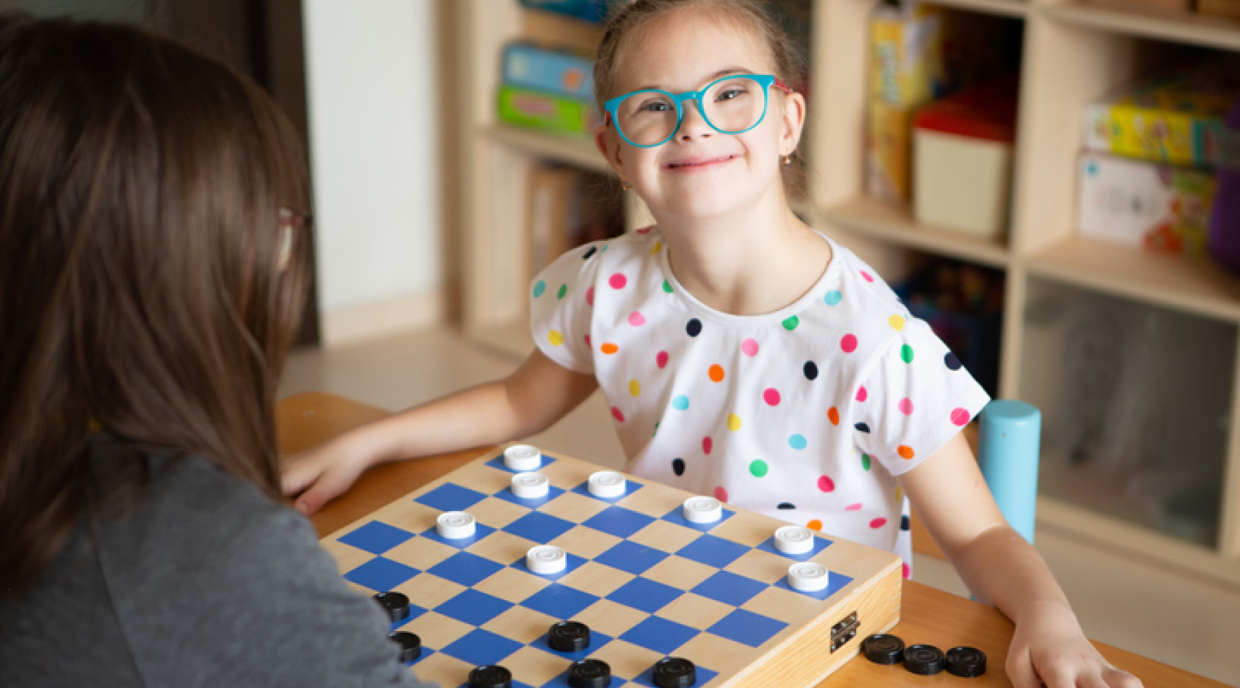 Girl with down syndrome having used the NDIS checklist playing chess with support worker
