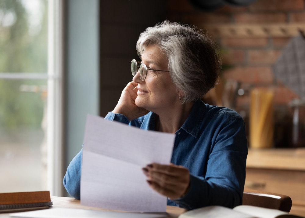 A thoughtful senior woman holding documents, considering a self managed aged care package for home care