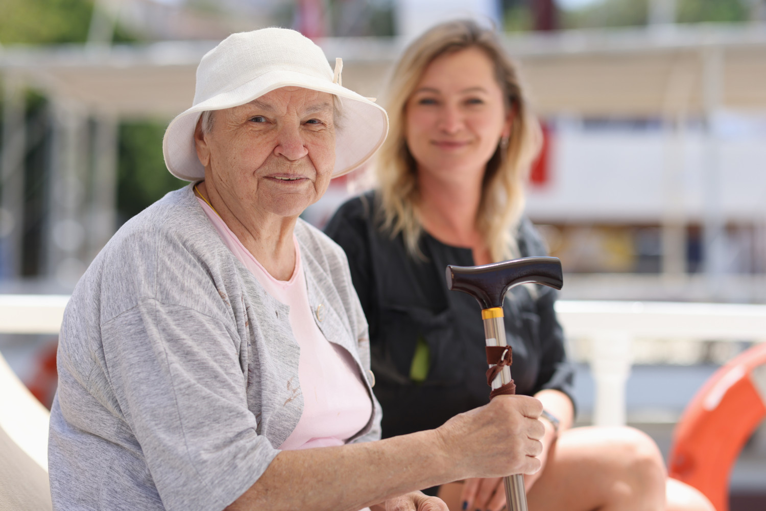 A cheerful elderly lady with a walking cane accompanied by her caregiver discussing self managed aged care packages.