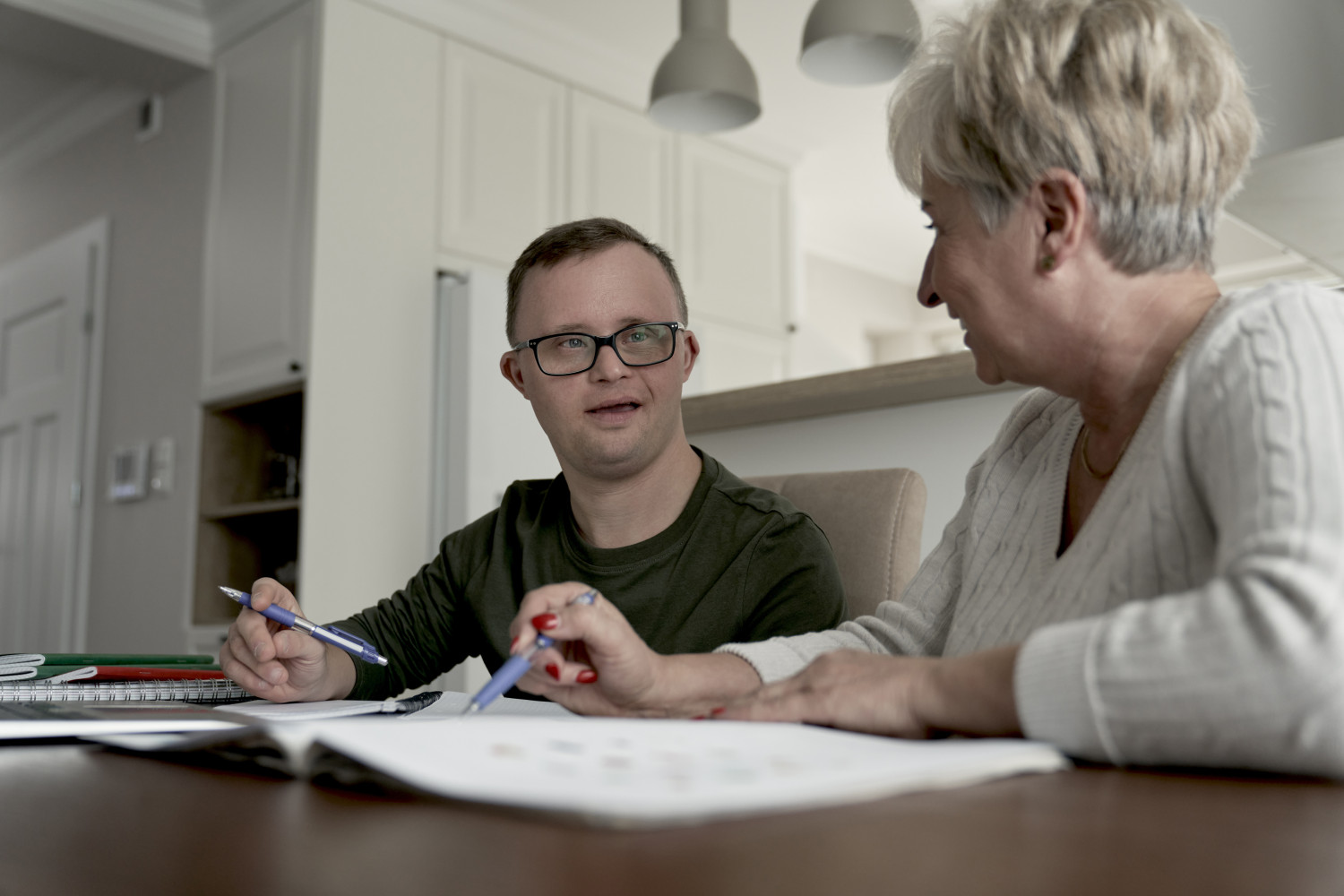 An man with Down Syndrome and a family member discussing the details of a self managed aged care package at home.