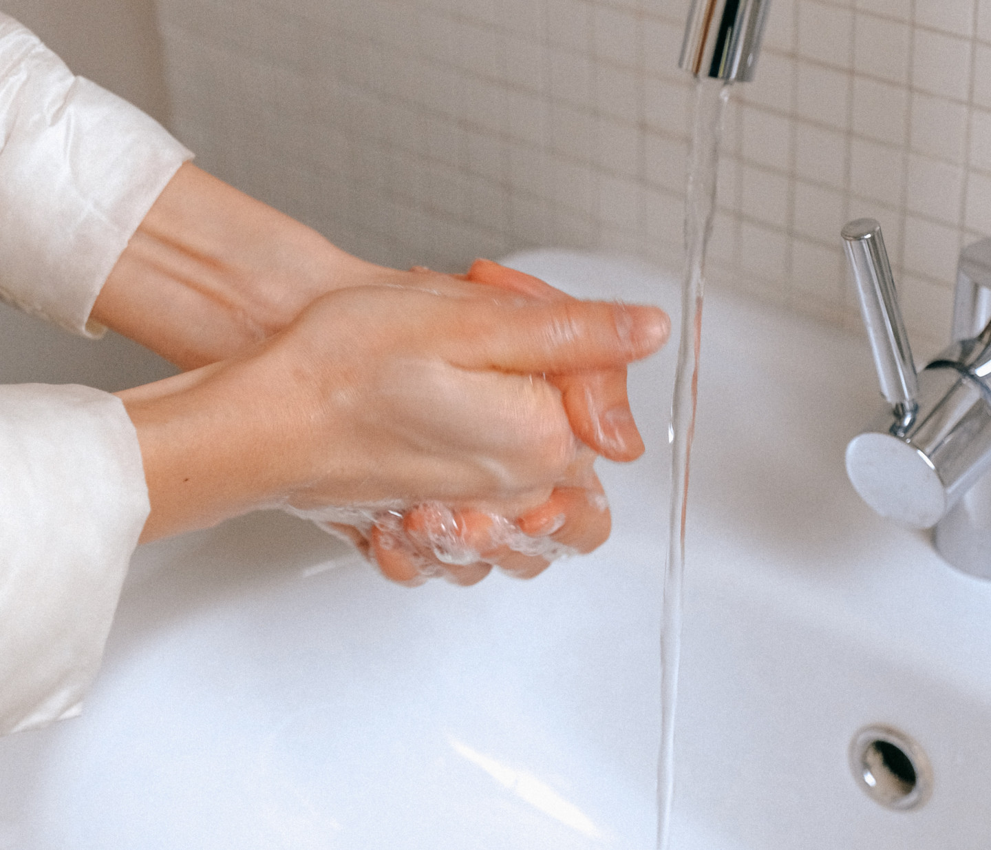 Close up of a person washing their hands under a sink with soap - COVID-19 Support - Focus Care